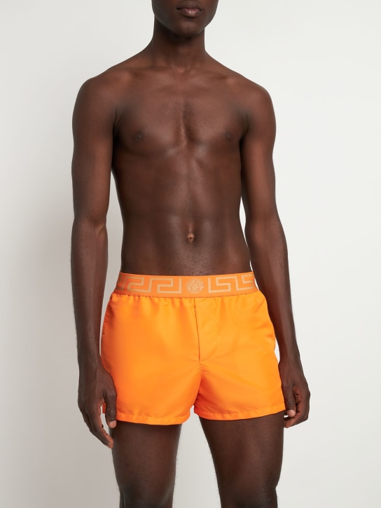 Versace: Shorts mare in techno con logo - Arancione/Oro - men_1 | Luisa Via Roma